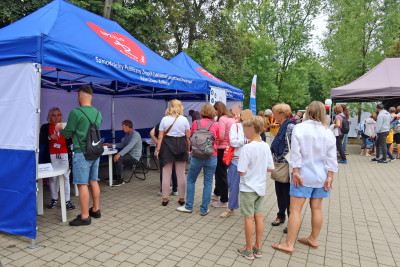 Stoisko SPZZLO Warszawa Żoliborz-Bielany z pacjentami ustawionymi w kolejce, widok boczny.