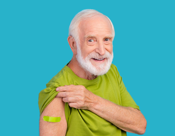 Na tle głównym starszy mężczyzna trzyma rękaw koszulki, pod którym znajduje się plaster po szczepieniu.