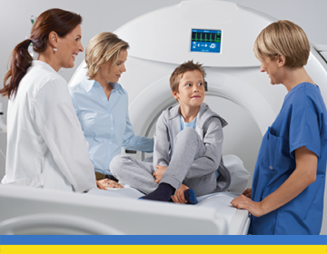 grupa lekarzy tłumaczy dziecku na czym polega badanie tomografii komputerowej w obecności mamy