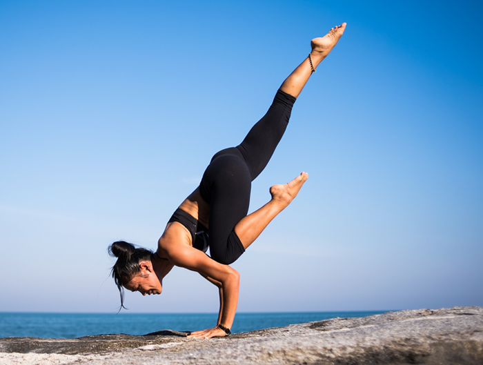 Młoda kobieta ćwiczy jogę nad oceanem