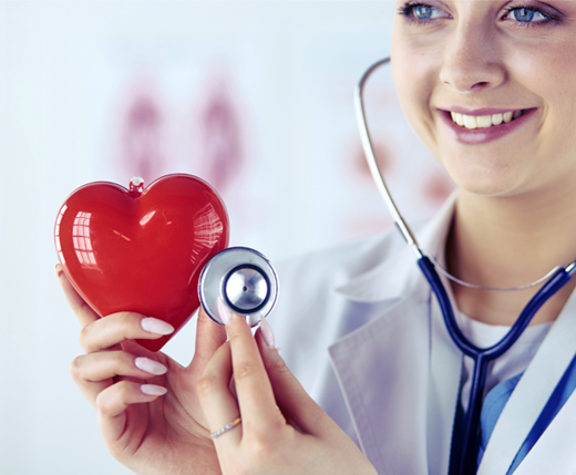 Lekarka w białym fartuchu uśmiecha się, trzymając czerwone serce i przykładając do niego stetoskop.