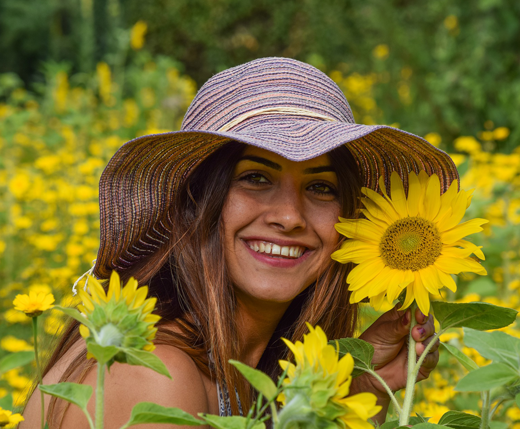 Piękna dziewczyna w kapeluszu chroniącym przed słońcem wśród słoneczników