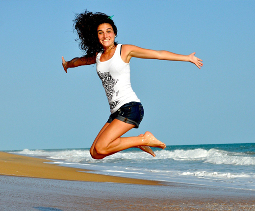 Zadowolona, uśmiechnięta dziewczyna skacze nad polskim morzem