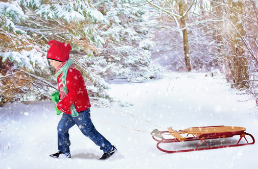 Chłopiec ciągnie sanki w zaśnieżonym parku