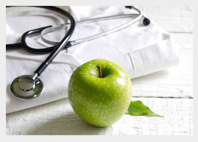 jabłko symbolizujące zdrowie oraz stetoskop leżący na fartuchu lekarskim