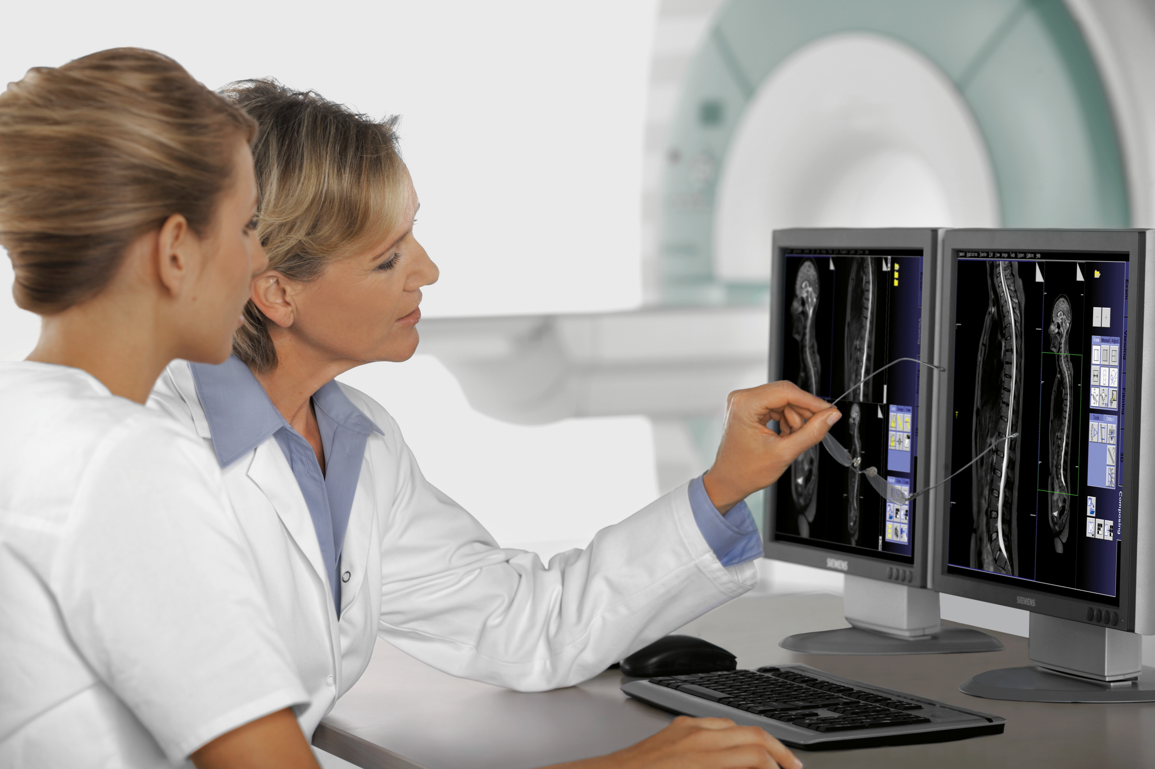 Dwie lekarki omawiające wynik badania rezonansu magnetycznego widoczny na monitorze komputera 
