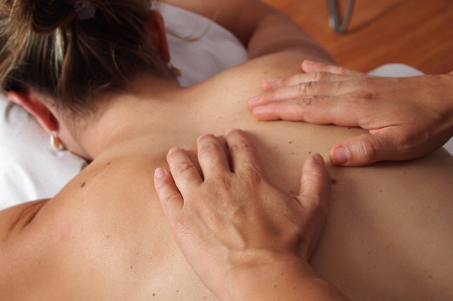 masażysta wykonuje masaż pleców młodej kobiecie